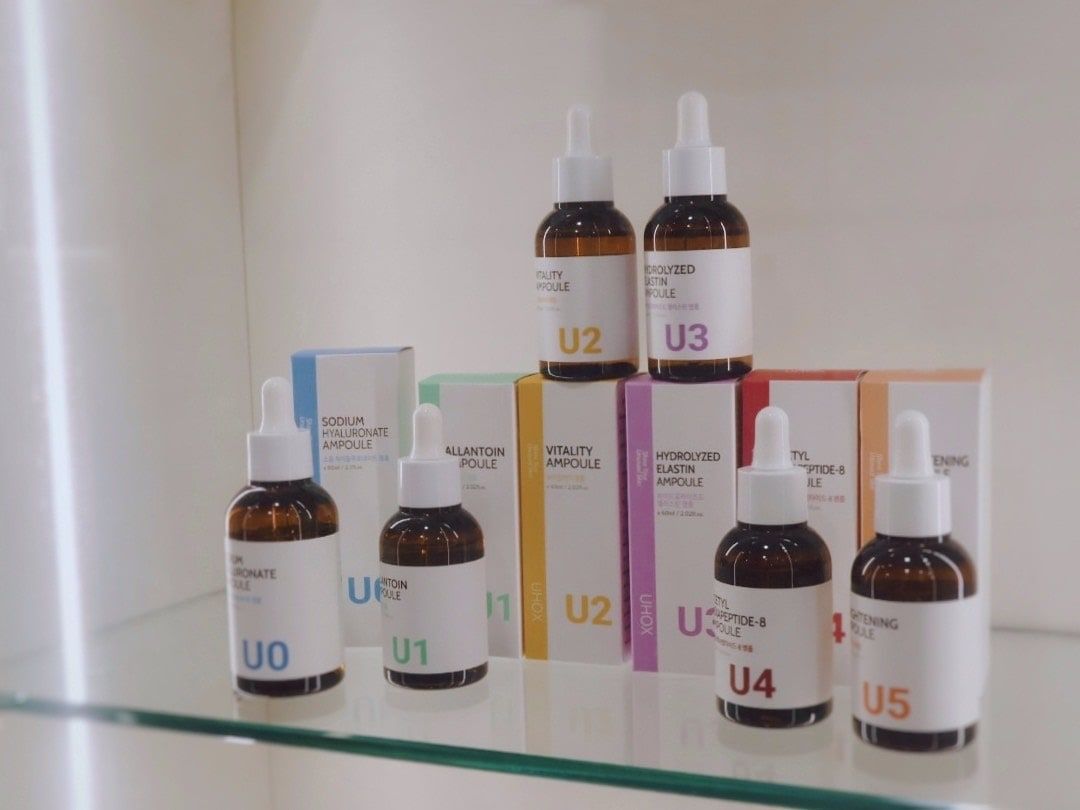 玻璃層架上的韓國安瓶產品,編號 U0 到 U5 的棕色滴管瓶與外盒